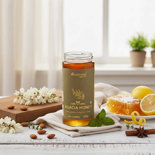 Barsana Magic and Bottle of Sanjeevani Acacia Honey on a table with lemon, honeycomb, and flowers.