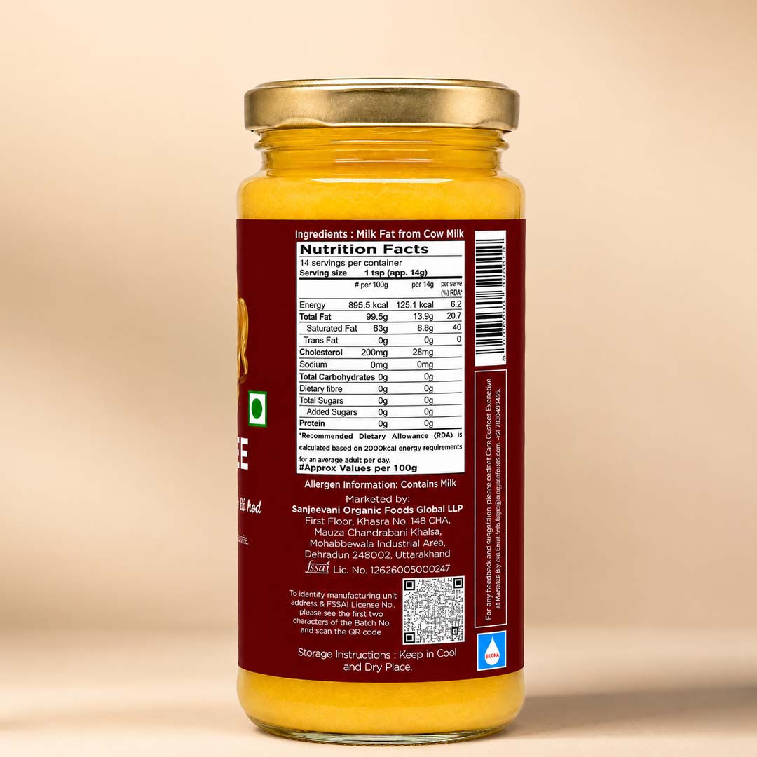Barsana Magic and A glass jar of mustard seed oil with a gold metal lid and a dark red label showing the nutrition facts and ingredients, set against a plain beige background.