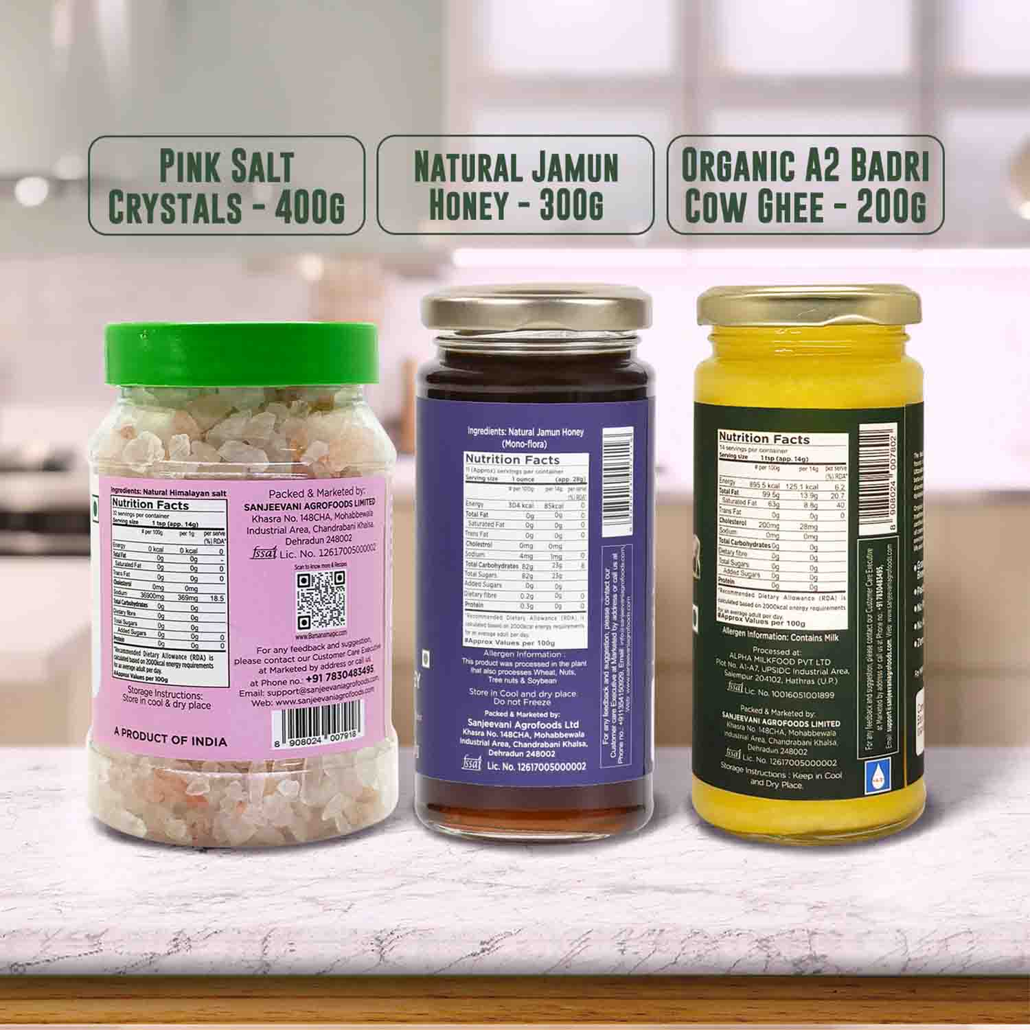 Barsana Magic and Three jars with labels for Pink Salt Crystals, Natural Jamun Honey, and Organic A2 Badri Cow Ghee on a kitchen counter.