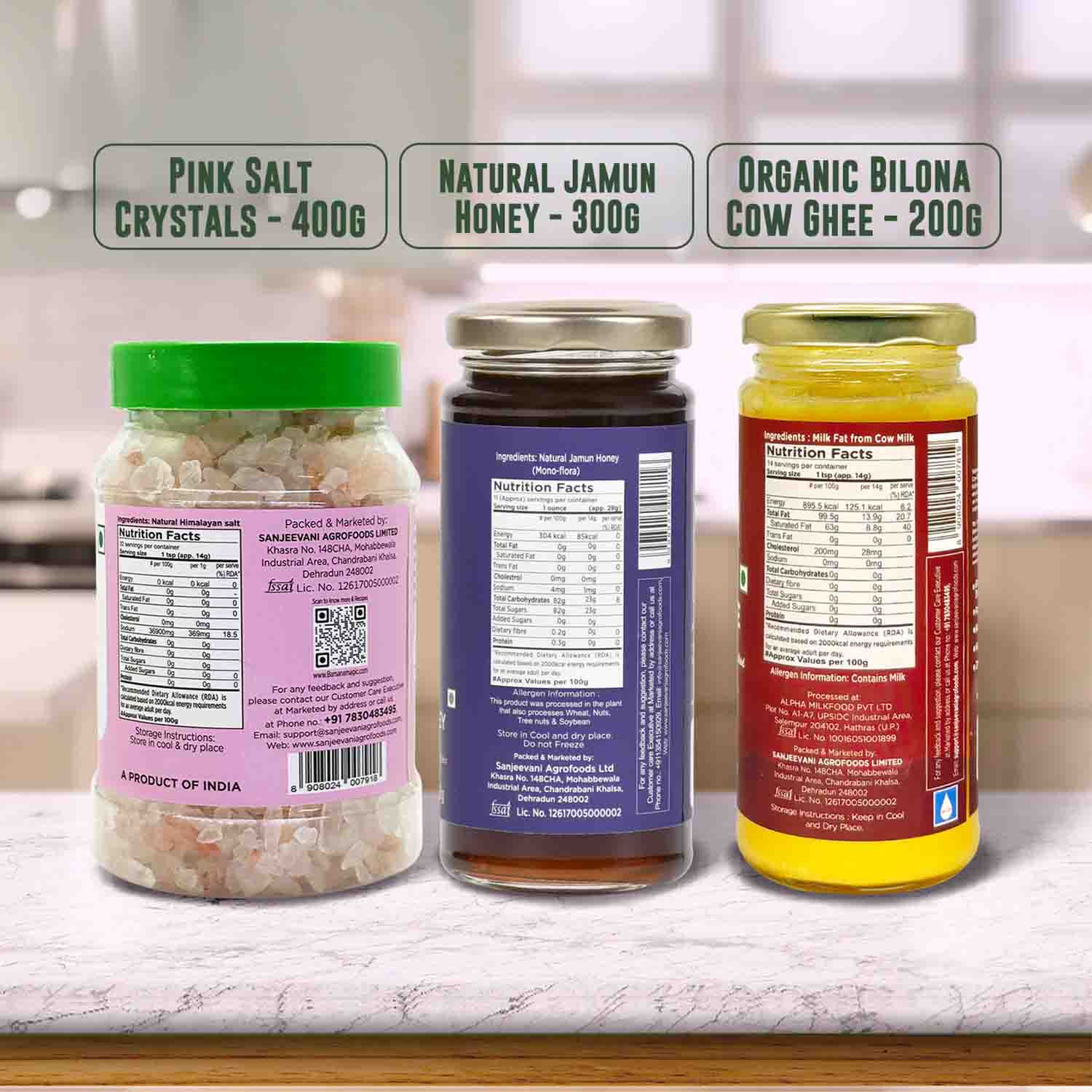 Barsana Magic and Three jars with labels for Pink Salt Crystals, Natural Jamun Honey, and Organic Bilona Cow Ghee on a kitchen counter.