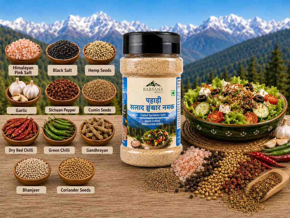 Barsana Magic and A bottle of Baraksha Salt & Spice Mix centered on a wooden table, surrounded by labeled spice bowls and ingredients including Himalayan pink salt, black salt, hemp seeds, garlic, cumin seeds, dried red chili, green chili, gandrayana, bhanjeer, and coriander seeds. A prepared salad sits in a bowl at right, with snowy mountains and a blue sky in the background.