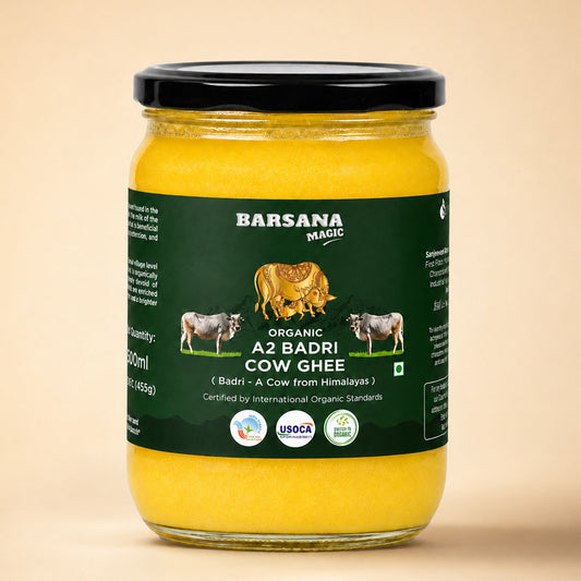 Barsana Magic and A glass jar of Barsana Magic Organic A2 Badri Cow Ghee with a black lid and a dark green label, set against a solid beige background.