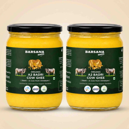 Barsana Magic and Two glass jars of A2 Badri Cow Ghee with black lids and dark green labels, displayed side-by-side on a light beige background.