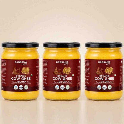 Barsana Magic and Three glass jars of Barsana Organic Cow Ghee (Rashmi and Bilona flavor) arranged side-by-side on a light beige reflective surface against a matching beige background.