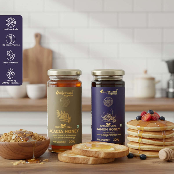 Barsana Magic and Two jars of honey from Sanjeevani Organics on a kitchen counter with a stack of pancakes and fruit.