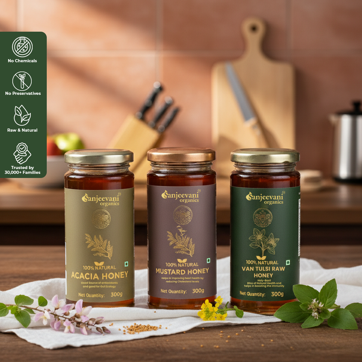 Barsana Magic and Three jars of Sanjeevani Organics honey on a kitchen counter with a cutting board and apples in the background.
