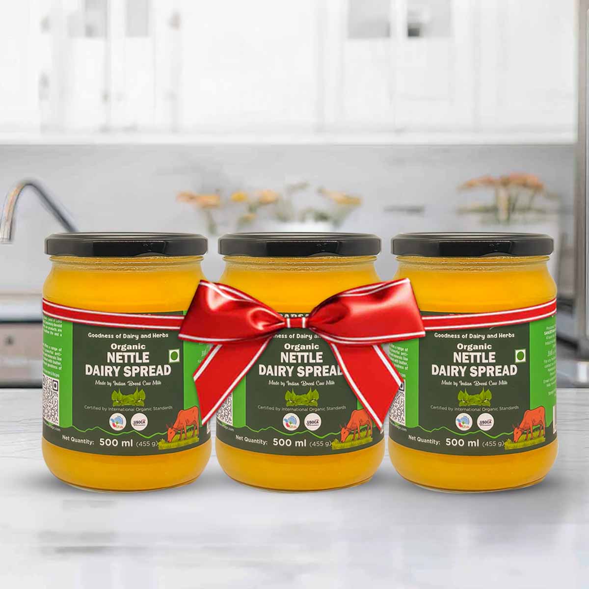 Barsana Magic and Three jars of Nettle Dairy Spread with a red ribbon on a kitchen counter.