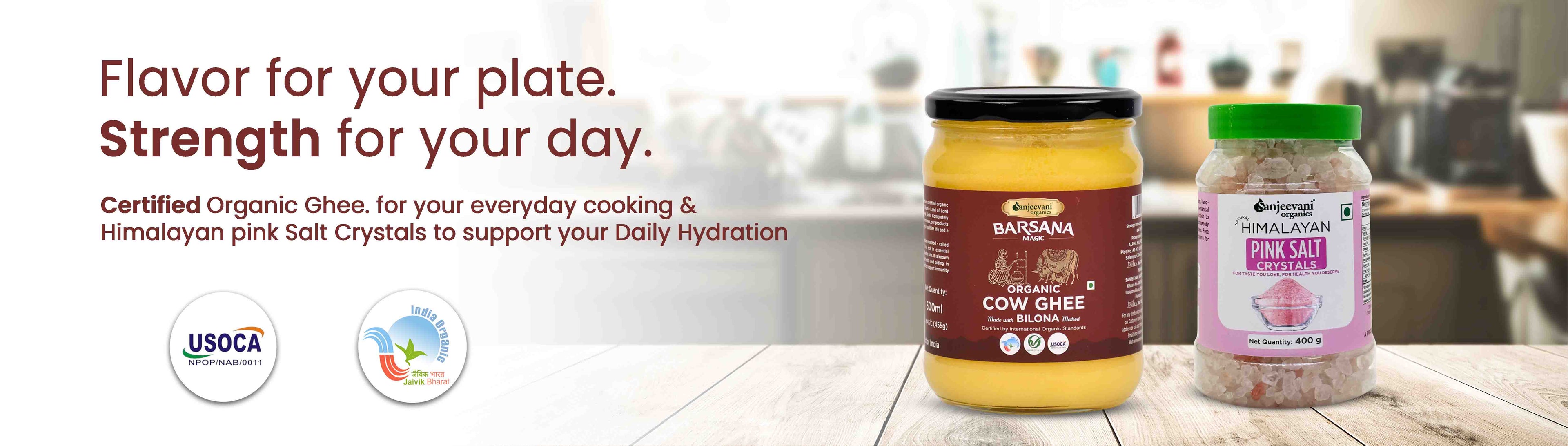 Barsana Magic and Two containers of organic ghee and pink salt on a wooden surface with a blurred kitchen background.