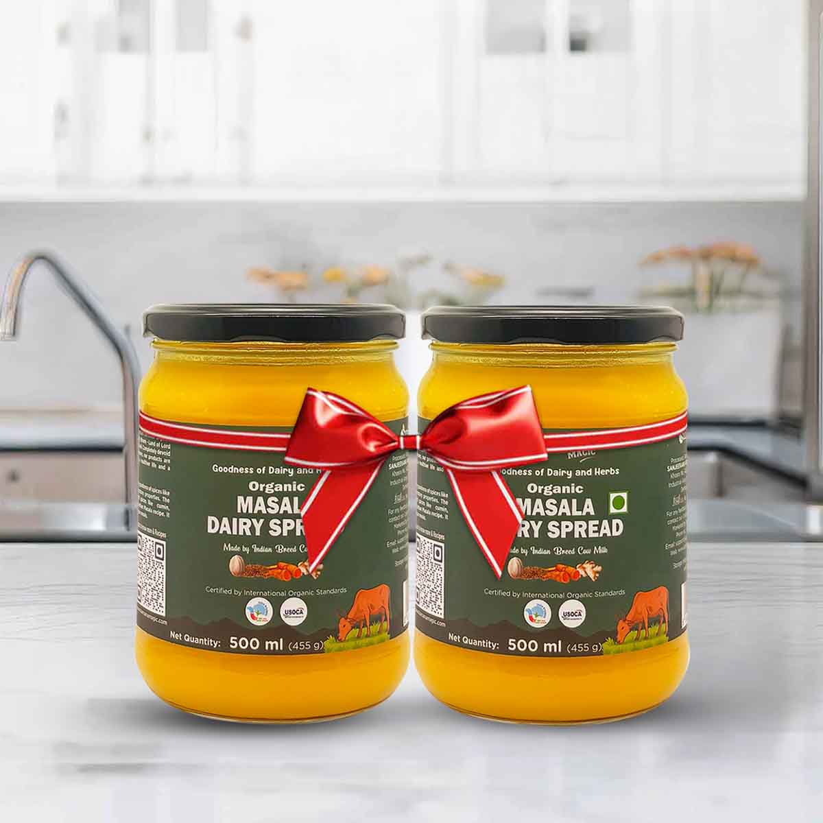 Barsana Magic and Two jars of Organic Masala Dairy Spread with a red ribbon on a kitchen counter.