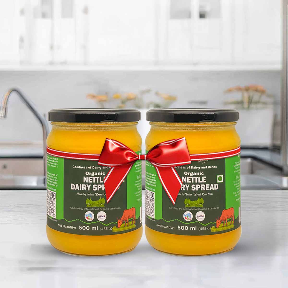 Barsana Magic and Two jars of organic nettle dairy spread with a red ribbon on a kitchen counter.