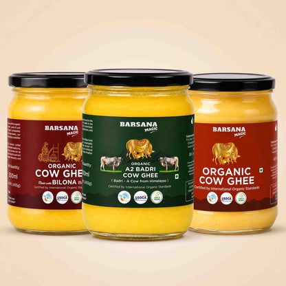 Barsana Magic and Three jars of Barsana Magic Organic Cow Ghee arranged together on a light beige background. The left jar has a maroon label, the center jar has a dark green label, and the right jar has a reddish-brown label, all showing the yellow ghee inside clear glass jars with black lids.