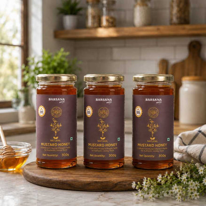 Barsana Magic and Three jars of Mustard Honey on a wooden board with a kitchen background.