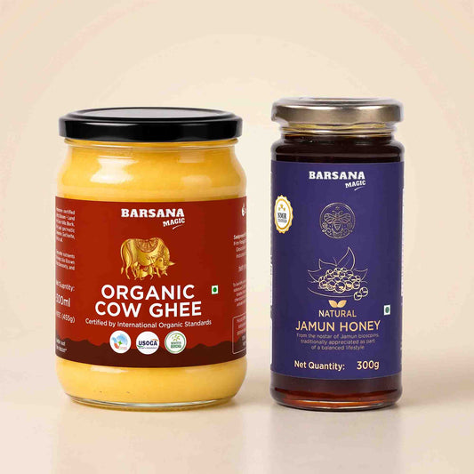 Barsana Magic and Two jars of  organic ghee and natural jamun honey on a light beige background. The left jar contains yellow organic cow ghee with a red label and black lid, and the right jar contains dark brown natural jamun honey with a blue label and silver lid.