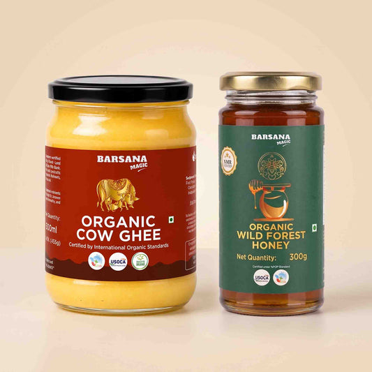 Barsana Magic and Two glass jars of  organic honey and cow ghee displayed side-by-side on a light beige background. The left jar contains yellow organic cow ghee with a black lid and a dark red label.