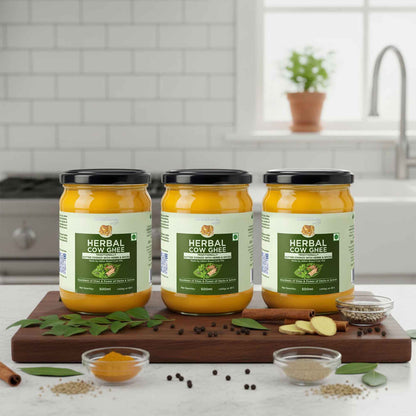 Barsana Magic and Three jars of Herbal Cow Ghee on a kitchen counter with ingredients around.