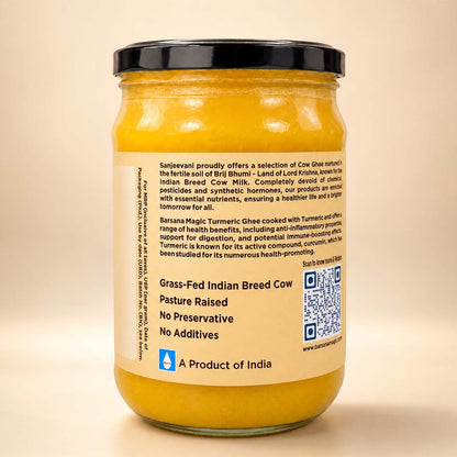 Barsana Magic and A glass jar of cow ghee with a black lid and a beige label, photographed against a plain beige background. The label contains text and a QR code, with the Sanskrit brand name 'Barasa Magic Turmeric' visible.
