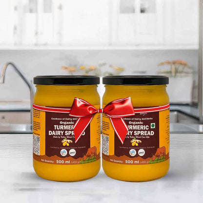 Barsana Magic and Two jars of organic turmeric dairy spread with a red ribbon on a kitchen counter.