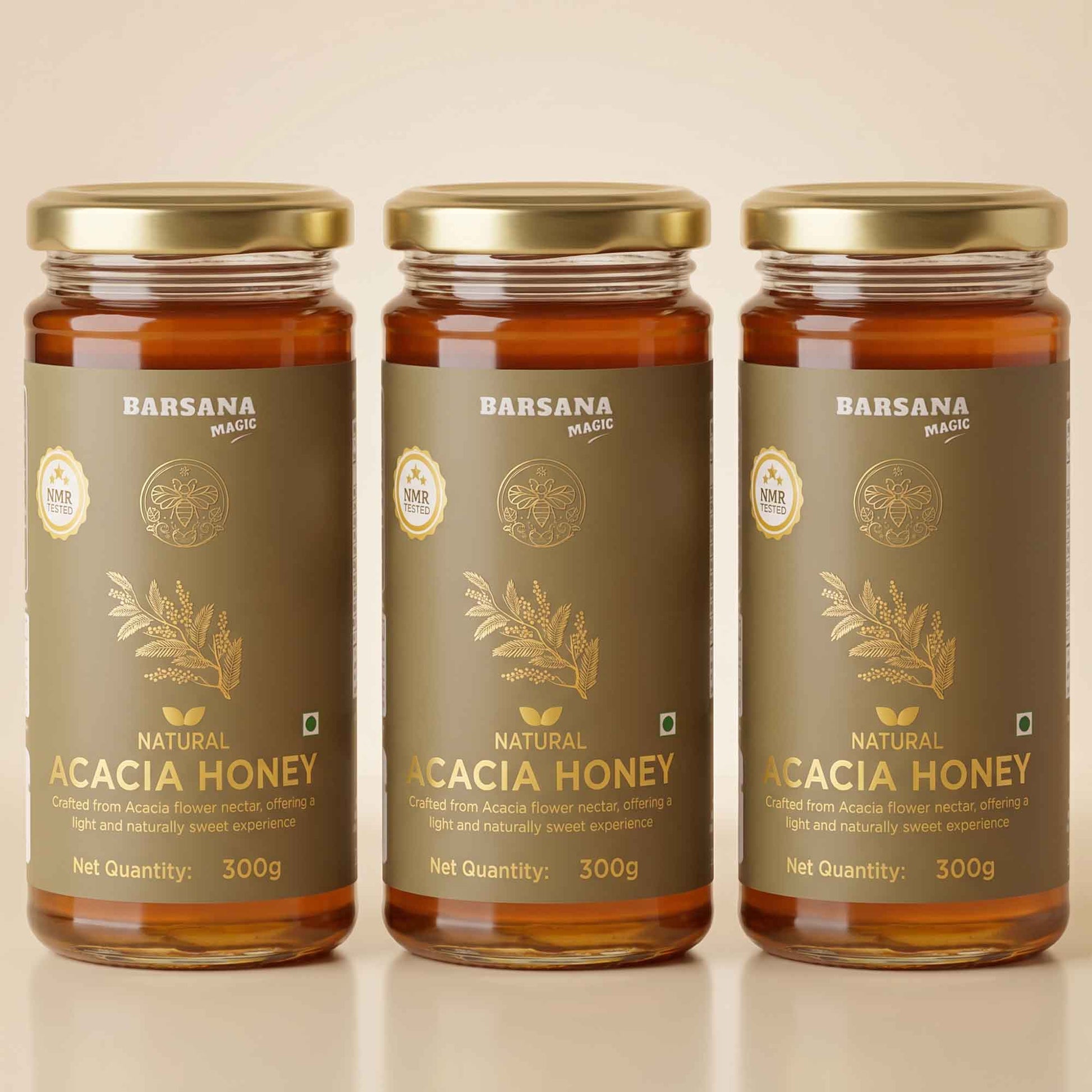 Barsana Magic and Three glass jars of Barsana Magic Natural Acacia Honey with gold lids and dark brown labels, arranged side by side on a light beige background.