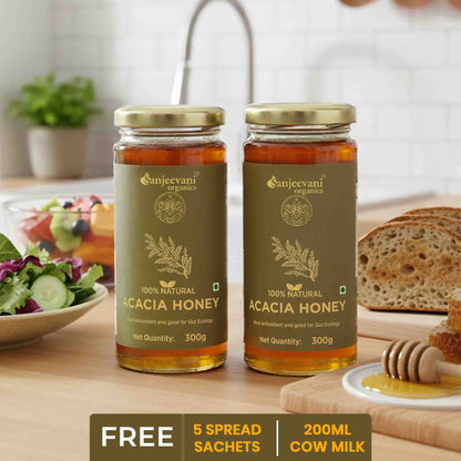 Barsana Magic and  Two jars of Sanjeevani Acacia honey on a table with a salad and bread in the background.