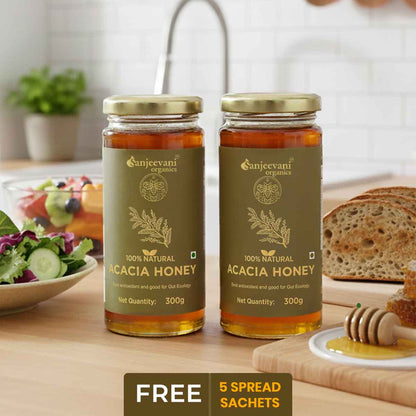 Barsana Magic and Two jars of Acacia honey from Sanjeevani Organics on a kitchen counter with bread and salad.