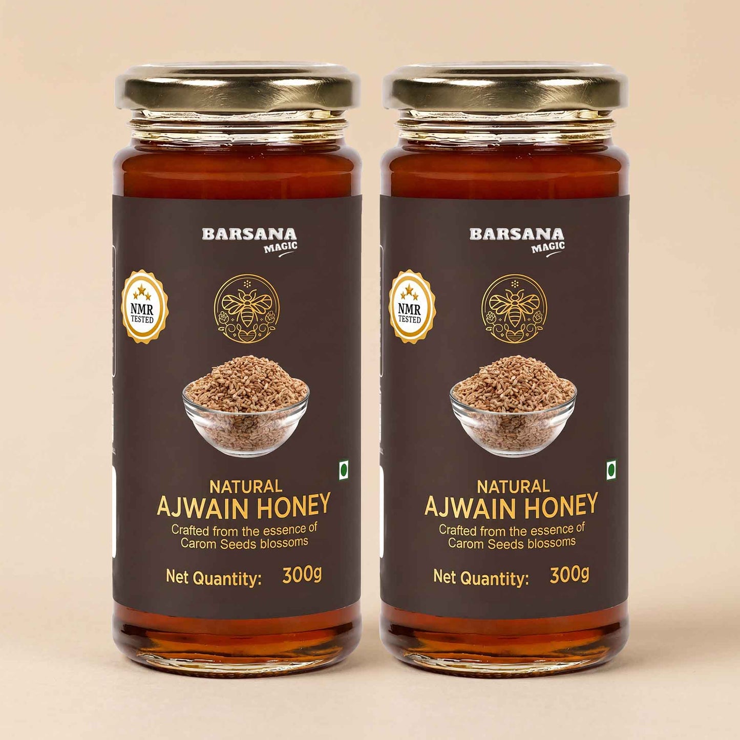 Barsana Magic and Two jars of Barsana Magic Natural Ajwain Honey, 300g each, arranged side-by-side on a light beige background. The jars are made of amber glass, showing the golden-brown honey inside, and are sealed with gold-colored metal lids.