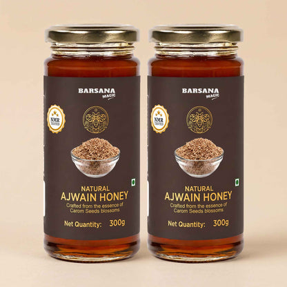 Barsana Magic and Two jars of Barsana Magic Natural Ajwain Honey, 300g each, arranged side-by-side on a light beige background. The jars are made of amber glass, showing the golden-brown honey inside, and are sealed with gold-colored metal lids.