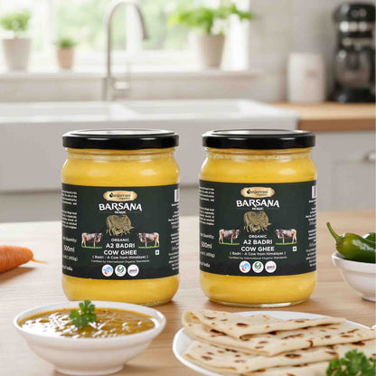 Barsana Magic and Two jars of cow ghee on a kitchen counter with food items around.