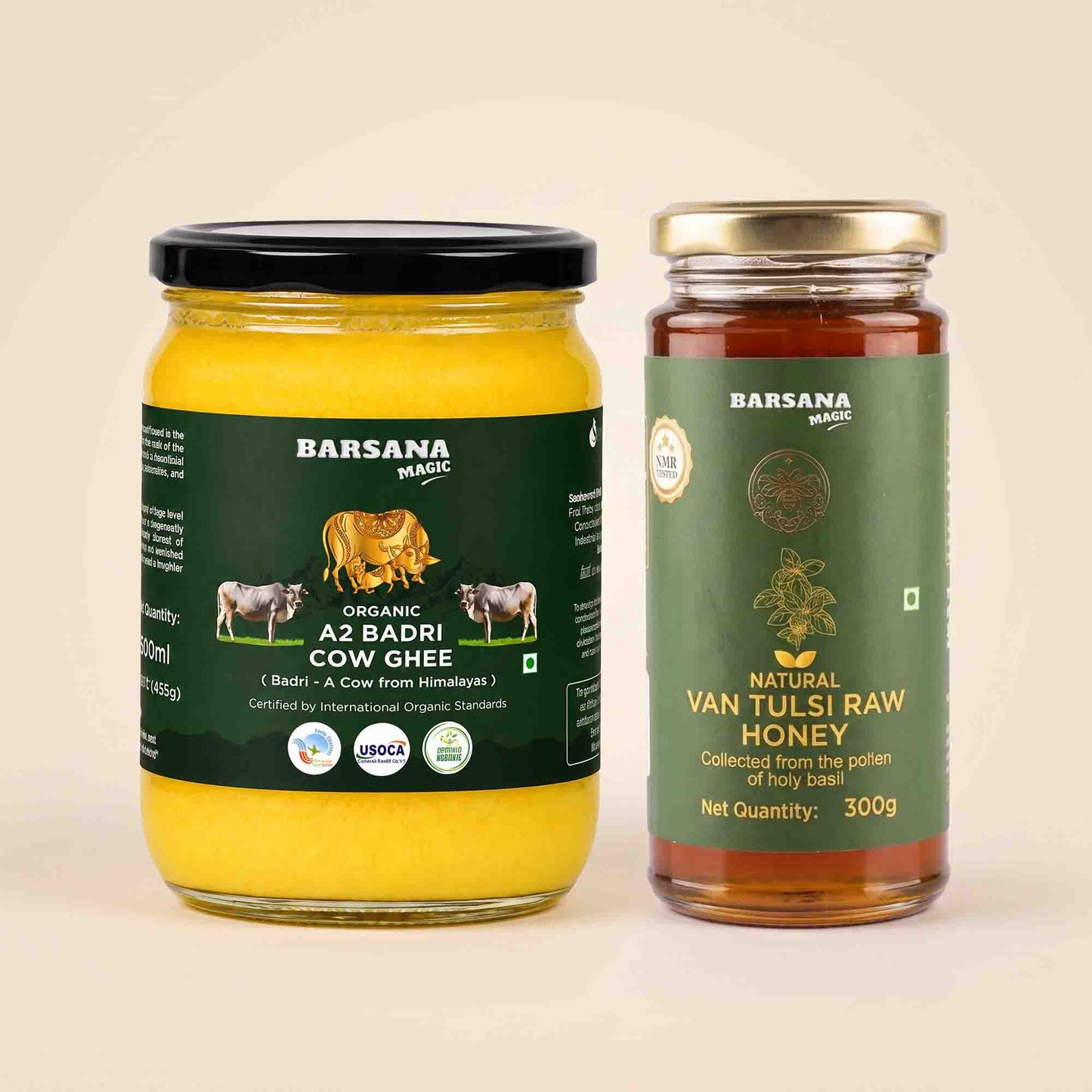 Barsana Magic and Two glass jars of Barsana brand products on a light beige background: a jar of Az Badri Cow Ghee with a black lid and yellow contents, and a jar of Van Tulsi Raw Honey with a gold lid and green label.