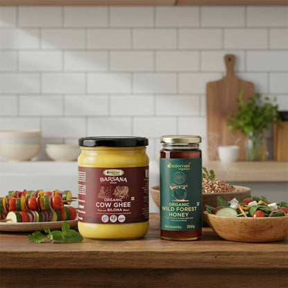 Barsana Magic and Two jars of organic products on a kitchen counter with a salad and vegetables in the background.