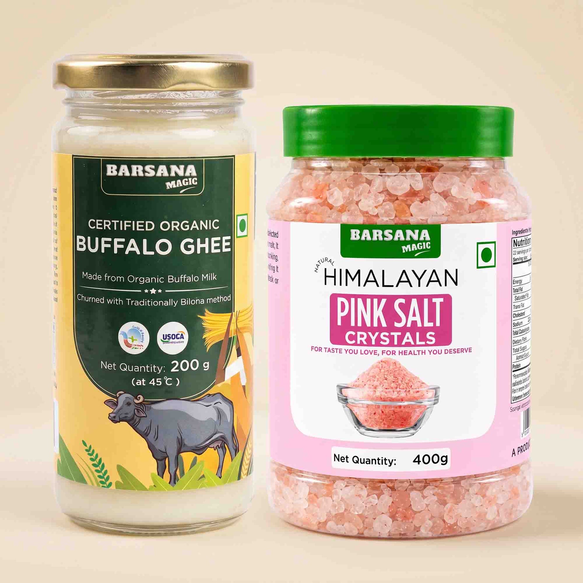 Barsana Magic and Two jars of Barsana Magic products on a light beige background: a glass jar of Certified Organic Buffalo Ghee with a gold lid and green/yellow label, and a plastic jar of Himalayan Pink Salt Crystals with a green lid and pink label.