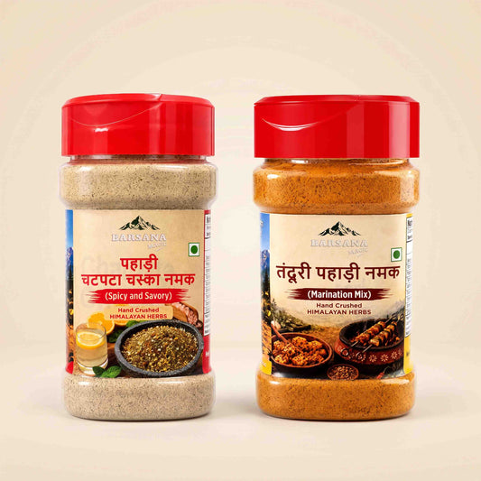 Barsana Magic and Two jars of Dalisana Hand Crusted Himalayan Naram mix shown side by side on a light beige background. The left jar contains a light beige spice blend labeled 'Spicy and Savory', and the right jar contains an orange-brown spice blend labeled 'Marination Mix', both with red lids.