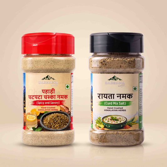 Barsana Magic and Two jars of Barmenara Maje spices on a light beige background: a red-capped Hand Crumbled Himalayan Salt jar on the left and a black-capped Hand Countered Himalayan Herbs jar on the right.
