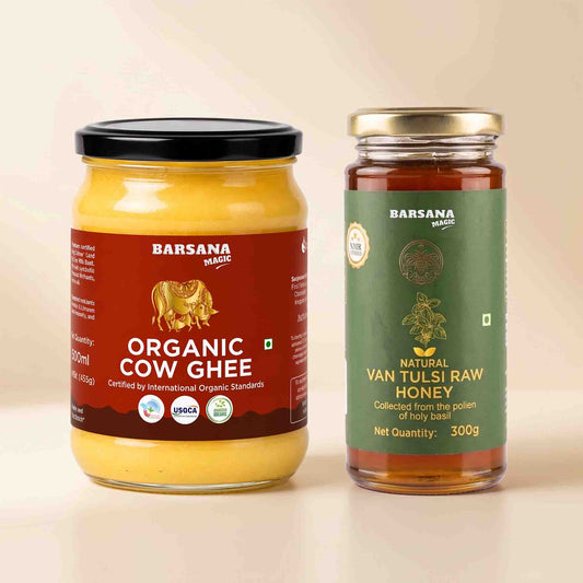 Barsana Magic and Two glass jars of products on a light beige background: a large jar of Organic Cow Ghee with a black lid and brown label, and a smaller jar of Natural Van Tulsi Raw Honey with a gold lid and green label.