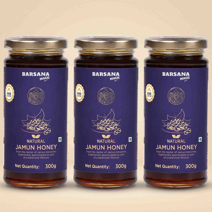 Barsana Magic and Three glass jars of Barsana Magic Natural Jamun Honey arranged side by side on a light beige background. Each jar has a dark blue label with gold and white text and graphics, topped with a silver metal lid.