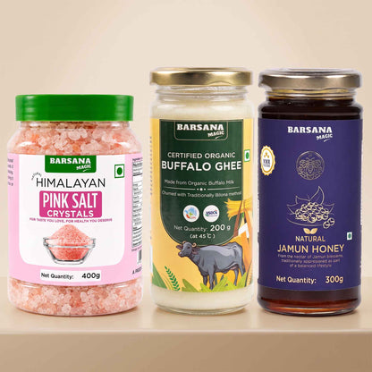 Barsana Magic and Three Barsana Magic products displayed side-by-side on a light beige shelf: a jar of Himalayan Pink Salt Crystals with a green lid, a glass jar of Certified Organic Buffalo Ghee with a gold lid, and a dark glass jar of Natural Jamun Honey with a purple lid.