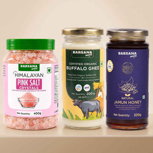Barsana Magic and Three Barsana Magic products displayed side-by-side on a light beige shelf: a jar of Himalayan Pink Salt Crystals with a green lid, a glass jar of Certified Organic Buffalo Ghee with a gold lid, and a dark glass jar of Natural Jamun Honey with a purple lid.