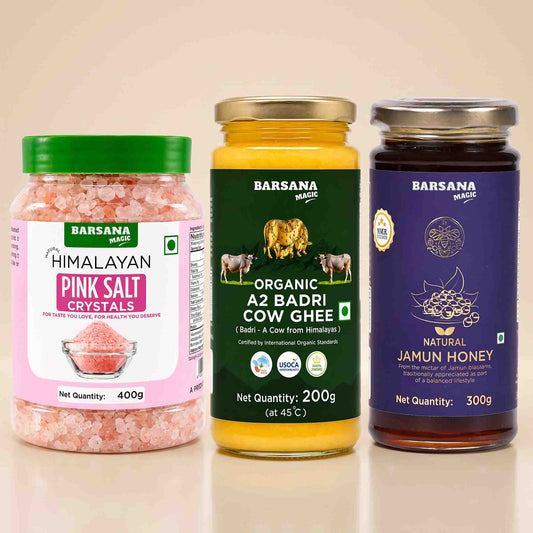 Barsana Magic and Three jars of Barsana Magic brand products arranged side-by-side on a reflective beige surface: Himalayan Pink Salt Crystals, Organic A2 Badri Cow Ghee, and Natural Jamun Honey.