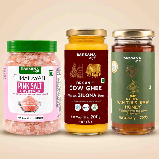 Barsana Magic and Three Barsana Magic products displayed side-by-side on a light beige background: Himalayan Pink Salt Crystals in a clear jar with a green lid, Organic Cow Ghee in a yellow jar with a gold lid, and Natural Van Tulsi Raw Honey in a dark green jar with a gold lid.