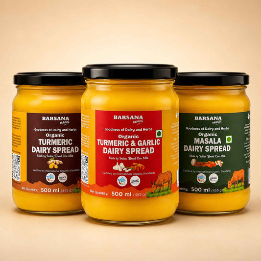 Barsana Magic and Three glass jars of Barsana Masala Dairy Spread arranged in a row on a beige background. The left jar is Organic Turmeric Dairy Spread with a dark brown label, the center jar is Organic Turmeric & Garlic Dairy Spread with a red label, and the right jar is Organic Masala Dairy Spread with a dark green label.