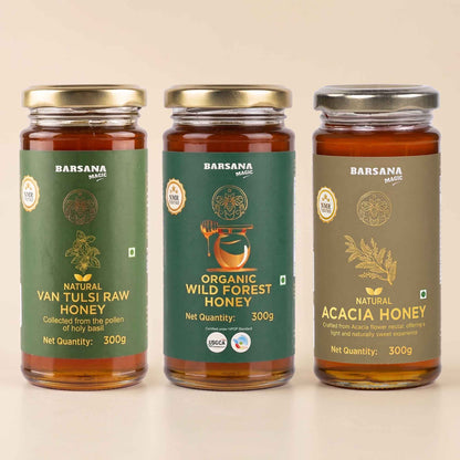 Barsana Magic and Three glass jars of Barsana brand honey arranged side by side on a light beige background. The left jar is labeled Natural Van Tulsi Raw Honey with a green label and gold lid.