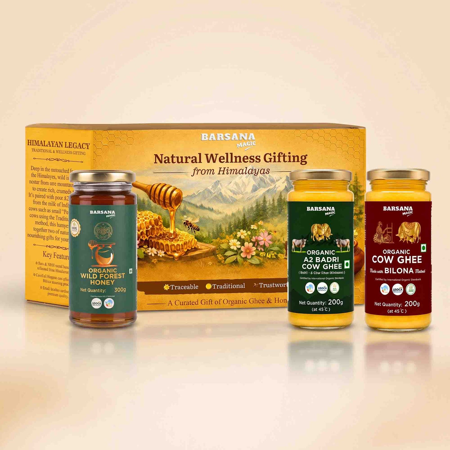 Barsana Magic and Legacy Natural Wellness Gifting set featuring a large yellow box and three glass jars of organic honey, cow ghee, and bilona milk powder arranged on a reflective white surface against a warm beige background.